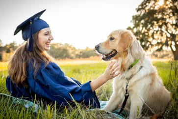 Amber Stien sits in the grass with her Golden Retriever Boomer